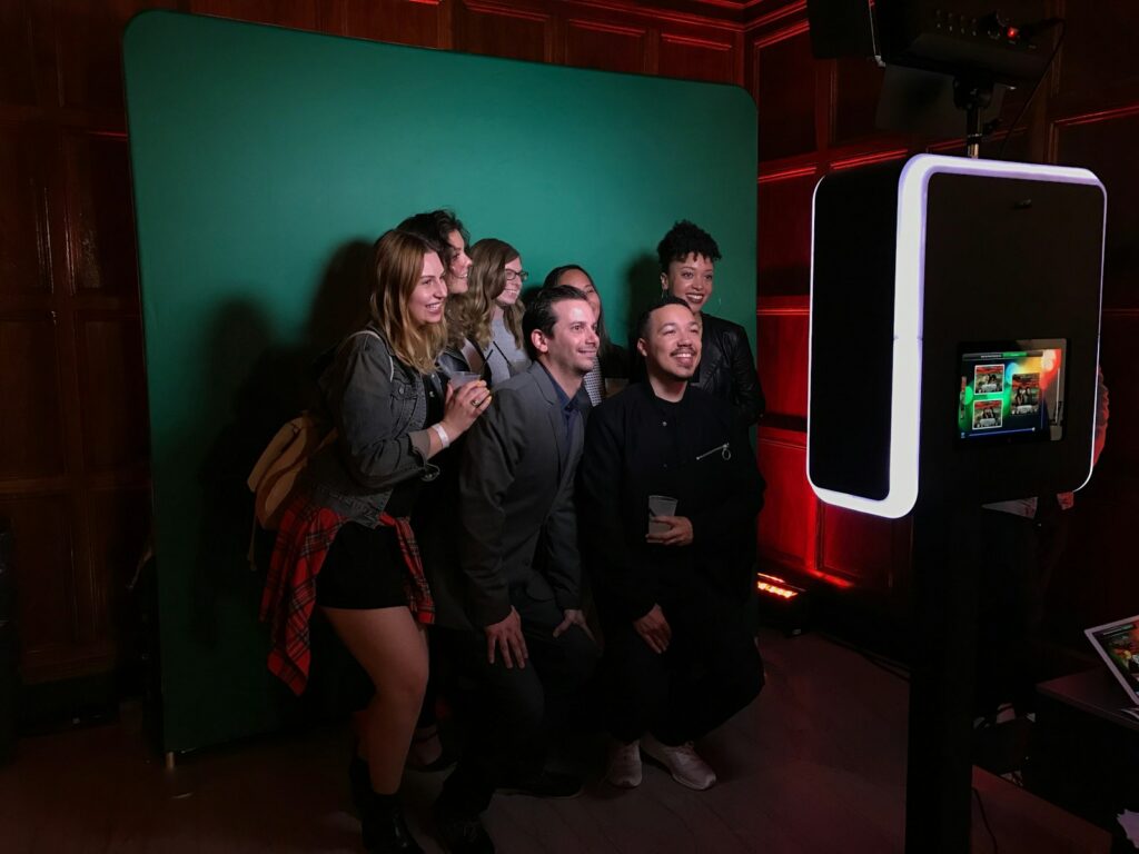A group of people standing in front of a green screen